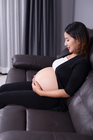 portrait of pregnant woman resting at home on sofaの写真素材