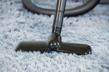 closed-up cleaning carpet floor with vacuum cleaner in the living roomの写真素材