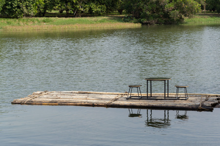 Bamboo rafts floating in the river and dining table and chairの写真素材