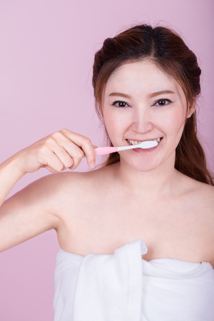 happy beautiful woman brushing her teeth on pink backgroundの写真素材
