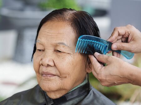 hand use comb to dressing the hair of a senior womanの写真素材