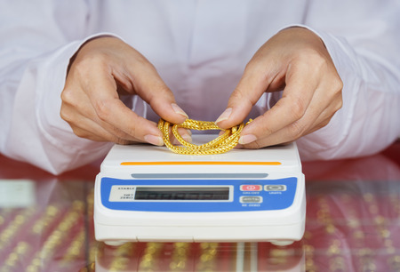 digital scales for weighing gold rings and necklaces with hand in storeの写真素材