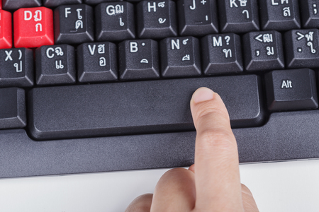 finger pushing space bar button on a keyboard of computer
