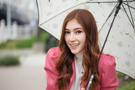 beautiful woman happy with umbrella in the gardenの写真素材