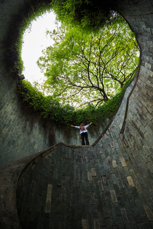 Woman hands up at underground crossing in tunnel at Fort Canning Park, Singapore