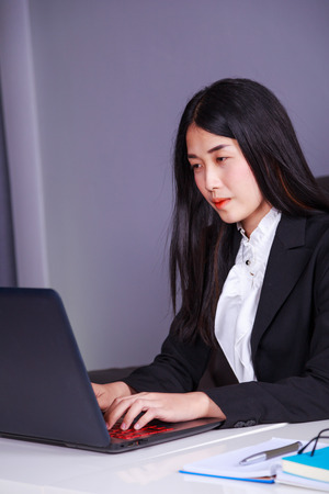 young business woman sitting at the desk and using laptop computer for her workの写真素材