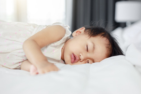 baby sleeping on bed in bedroom at homeの写真素材