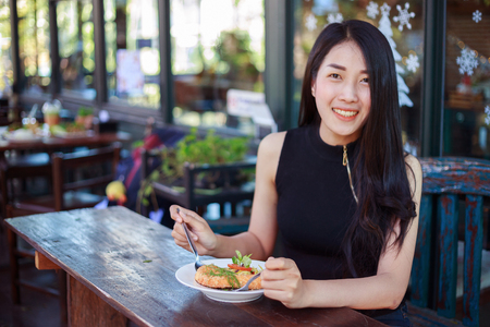 young woman eating food in a restaurant の写真素材