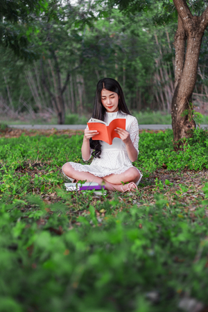 young woman reading a book in the parkの写真素材