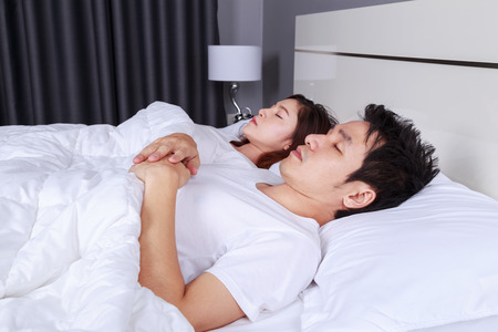 young couple sleeping on a comfortable bed in bedroom at homeの写真素材