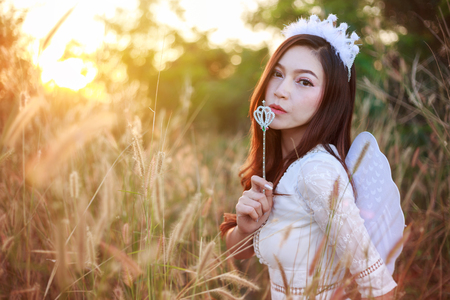 beautiful angel woman in a grass field with sunlightの写真素材