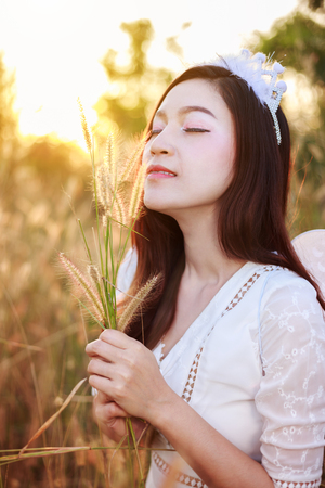 beautiful angel woman in a grass field with sunlightの写真素材
