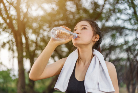 young sporty woman drinking water in the parkの写真素材
