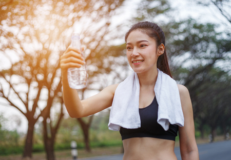 young sporty woman with bottle of water in the parkの写真素材