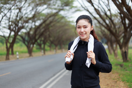 young sporty woman with white towel resting after workout sport exercises outdoors at the parkの写真素材