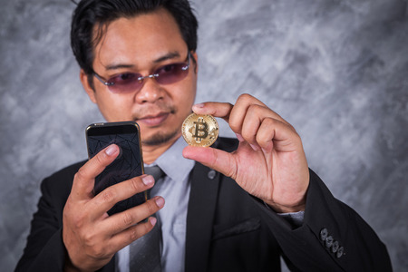 young business man with bitcoin and using mobile phoneの写真素材