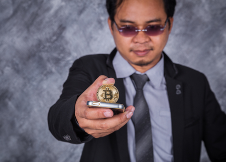 young business man with bitcoin and using mobile phoneの写真素材