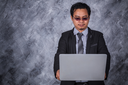 young business man holding laptop with wall backgroundの写真素材