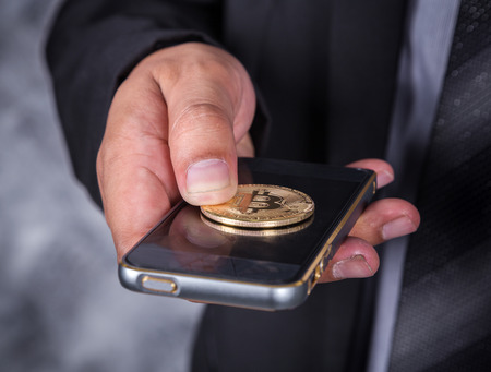 close up business man with bitcoin and using a mobile phoneの写真素材