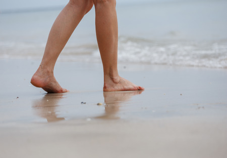 Close up of female legs walking on the beachの写真素材