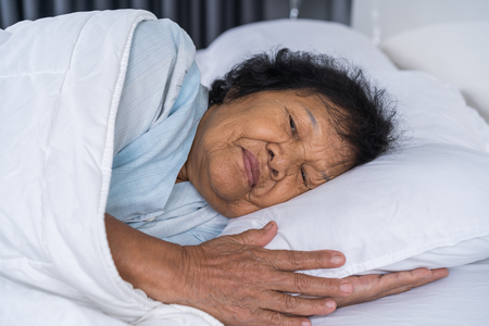 happy senior woman sleeping on a bedの写真素材