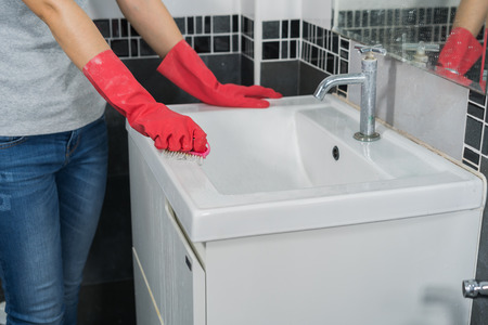 hand cleaning bathroom sink with a brush