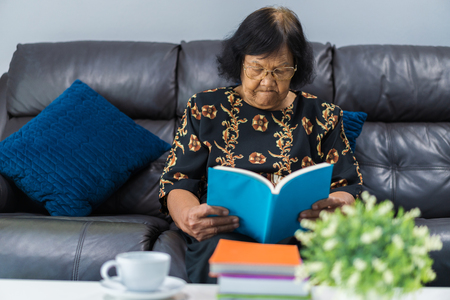 senior woman reading a book in living roomの写真素材