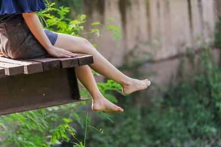 woman's legs hanging over edge of a wooden jettyの写真素材