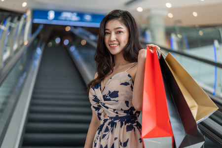 happy young woman with shopping bags on escalator in mallの写真素材