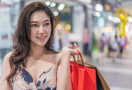 happy young woman with shopping bags in mallの写真素材