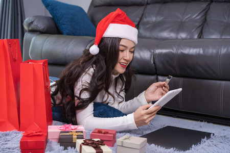 woman in santa hat shopping online for Christmas gift with digital tablet in the living roomの写真素材