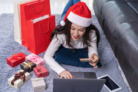 woman in santa hat shopping online for Christmas gift with laptop in the living roomの写真素材