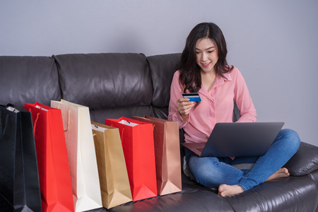 happy woman using laptop computer for online shopping with credit card in the living roomの写真素材