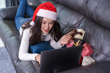 woman in santa hat shopping online for Christmas gift with laptop in the living roomの写真素材