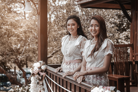 two young woman in Thai traditional dress at wooden houseの写真素材