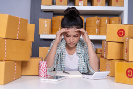 stressed young entrepreneur woman and courier parcel box at home office