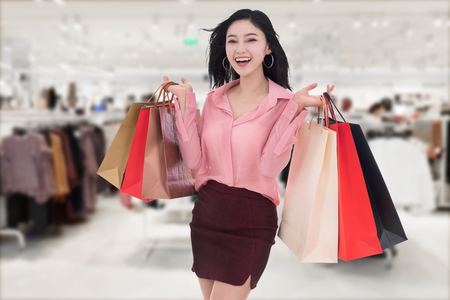 cheerful young woman holding shopping bag at the mallの写真素材
