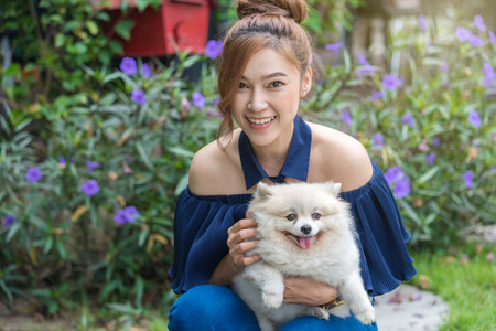 Woman hug with pomeranian dog in the gardenの写真素材