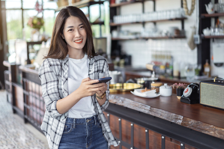 happy woman using smartphone in a cafeの写真素材