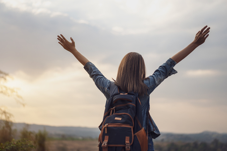 traveler woman with backpack standing with arms raisedの写真素材