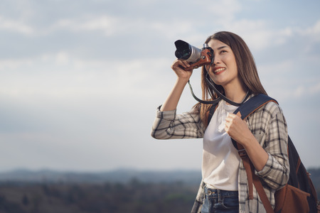tourist woman taking a photo with her camera in nature