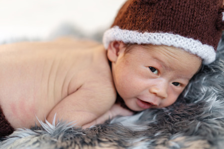 newborn baby in bear hat on a fur bedの写真素材