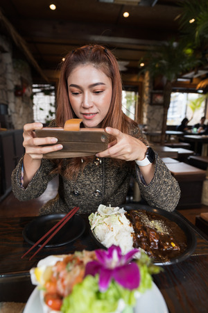 woman using smartphone taking a photo of food in the restaurantの写真素材