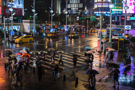 Taipei, Taiwan- 11 June, 2019: people crossing street in front of Ximending Shopping District with falling rain at night in Taipei, Taiwan. Ximending is the famous fashion, night Market and street food in Taipei.のeditorial素材
