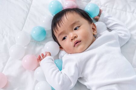 cheerful baby playing color ball on a bedの写真素材