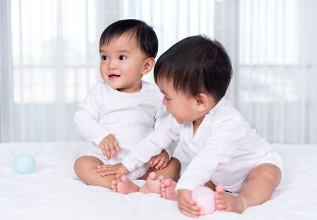 cheerful twin babies playing color ball on a bedの写真素材