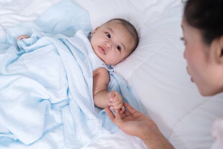 baby hand holding finger of mother on a bedの写真素材