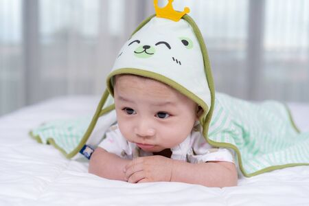 happy baby lying on bed under blanket in a bedroom