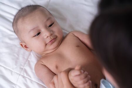 baby hand holding finger of mother on a bed