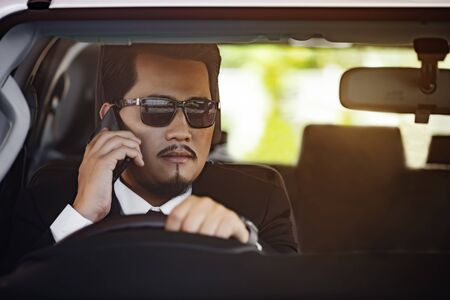 young business man talking with mobile phone and driving a car
